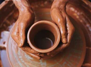 Hands working clay on wheel