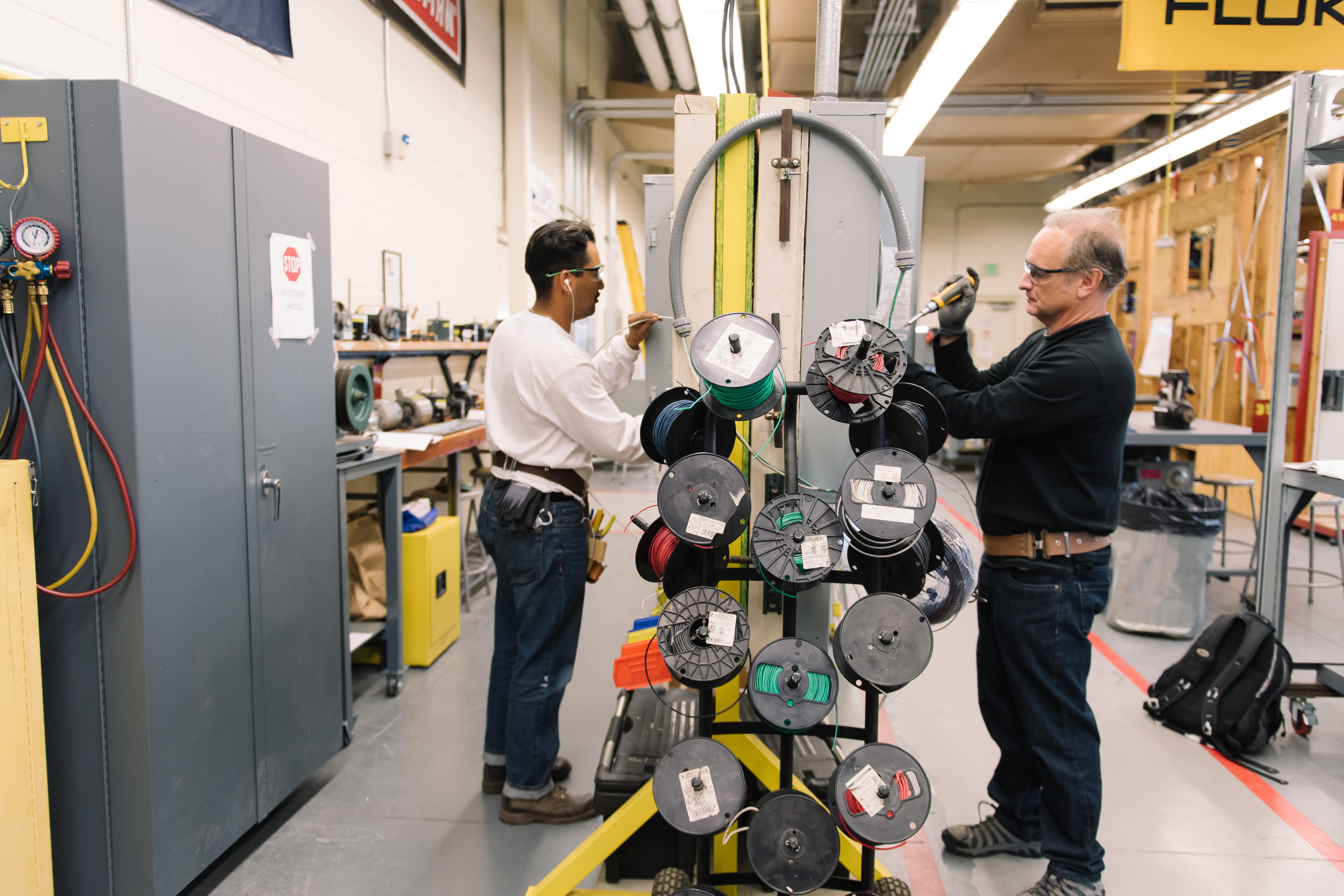 two men interact with some wiring equipment