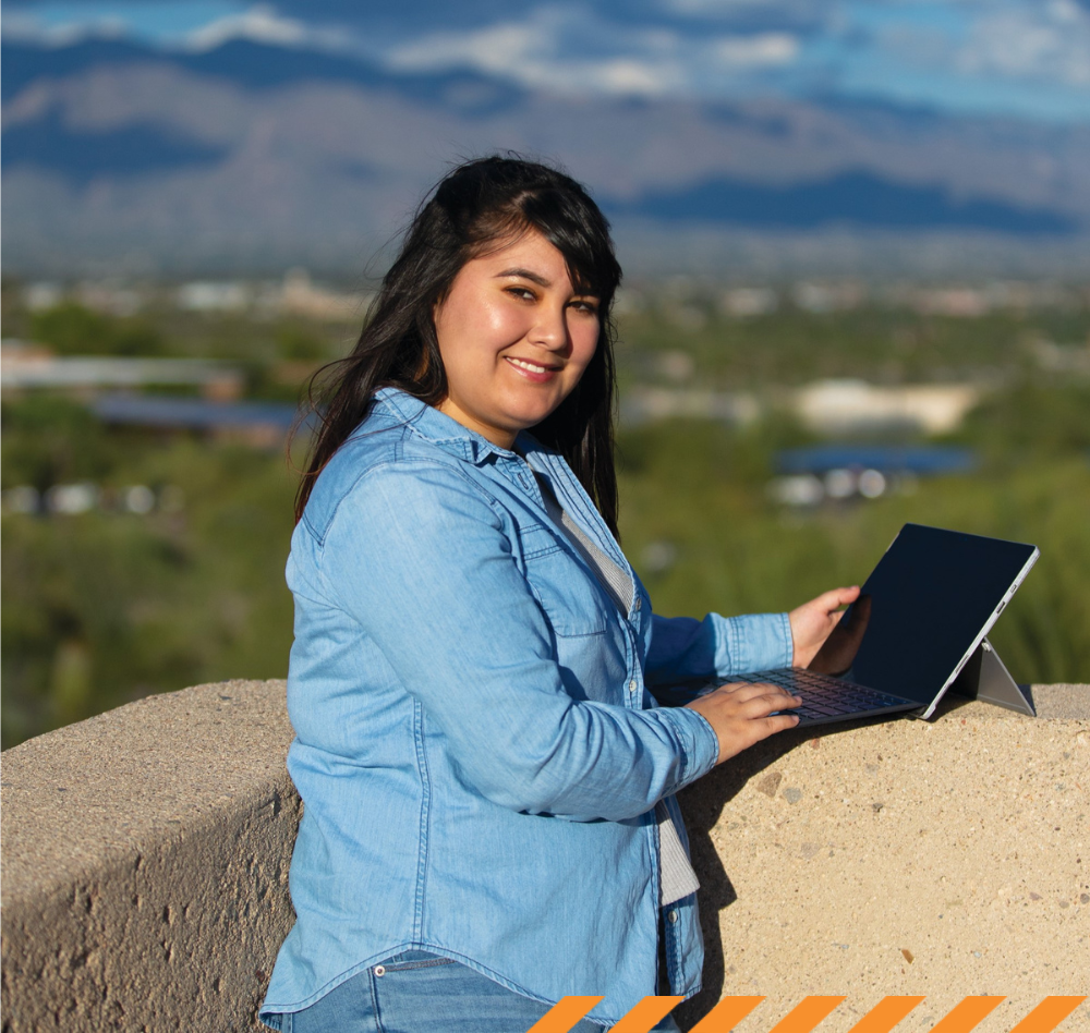 student at laptop with mountains in background